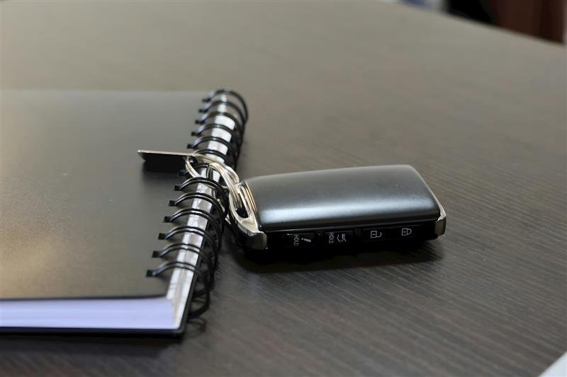 Chave de carro ao lado de um caderno sobre uma superfície clara