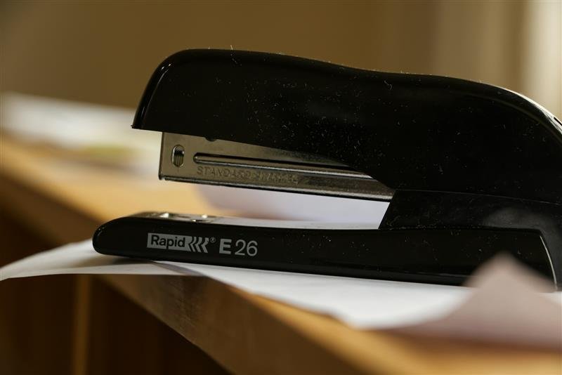 Grampeador preto sobre uma mesa com papéis