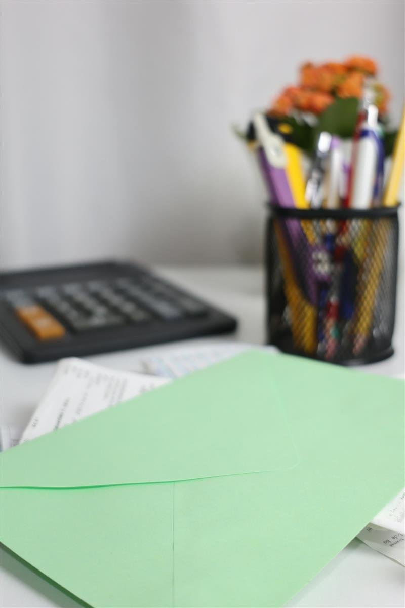 Envelope verde sobre papéis, ao lado de uma calculadora