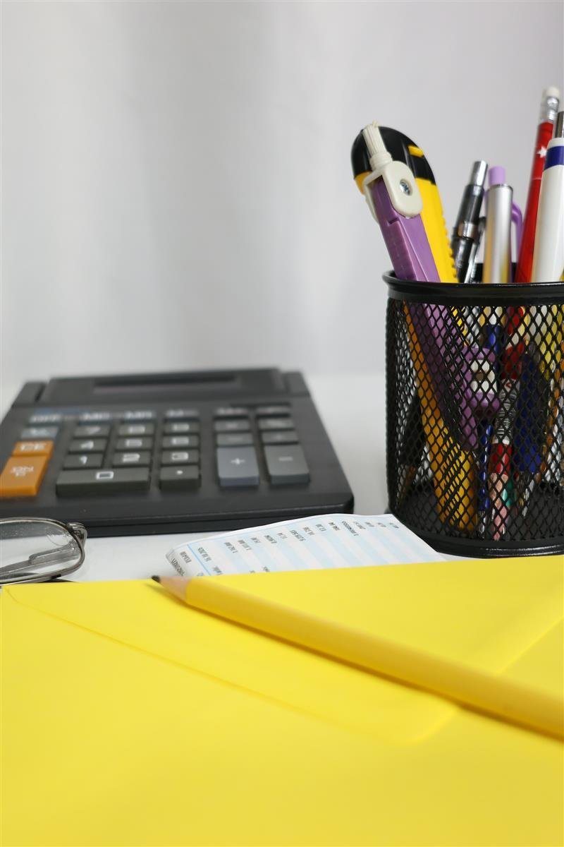 Mesa com calculadora, canetas e um envelope amarelo