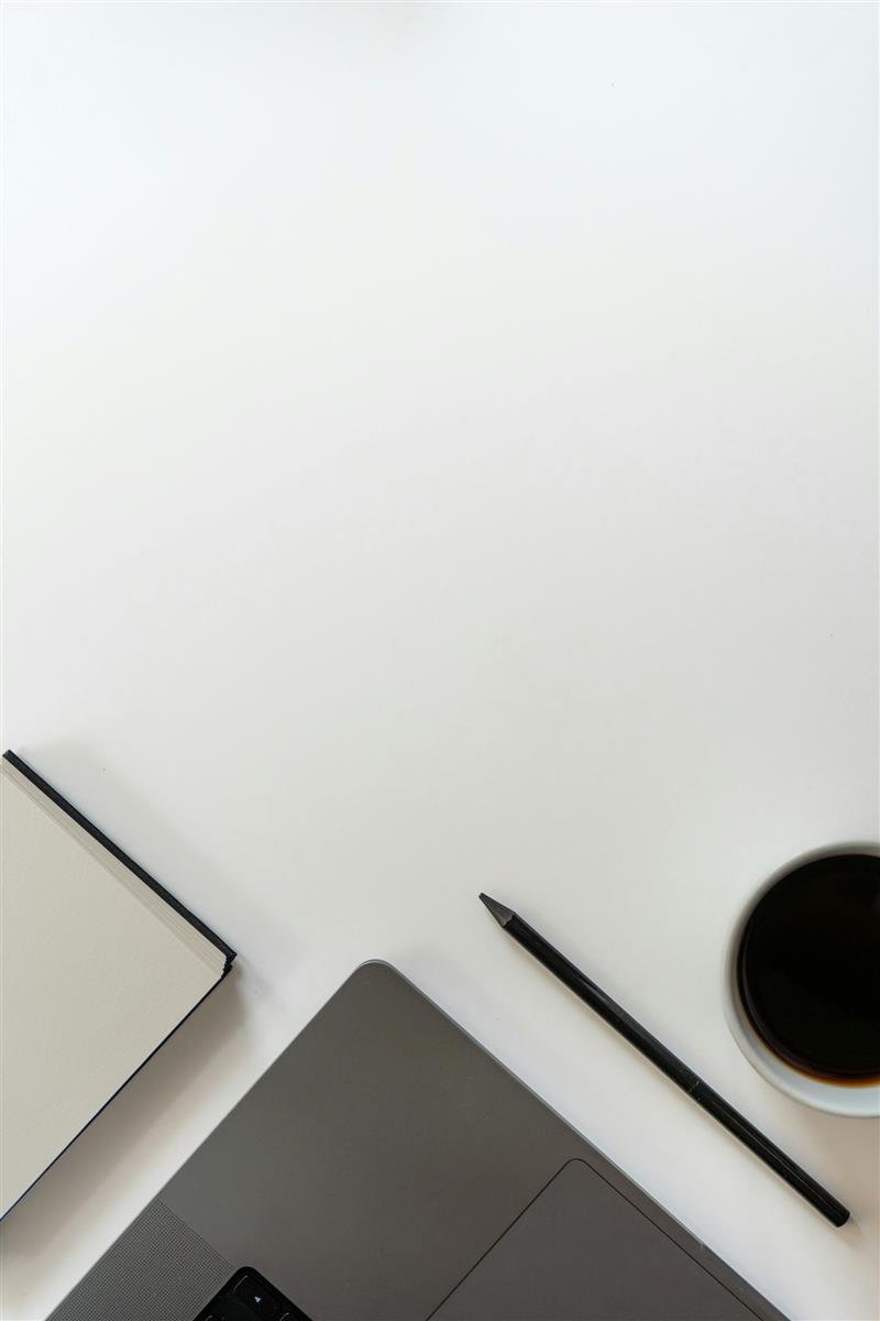 Mesa clara com notebook aberto, caderno e xícara de café