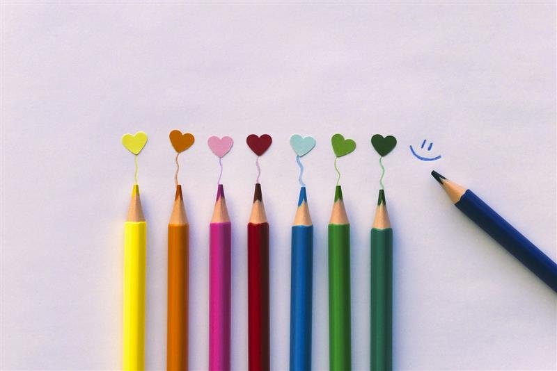 Lápis de cor coloridos desenhando corações e uma carinha sorridente