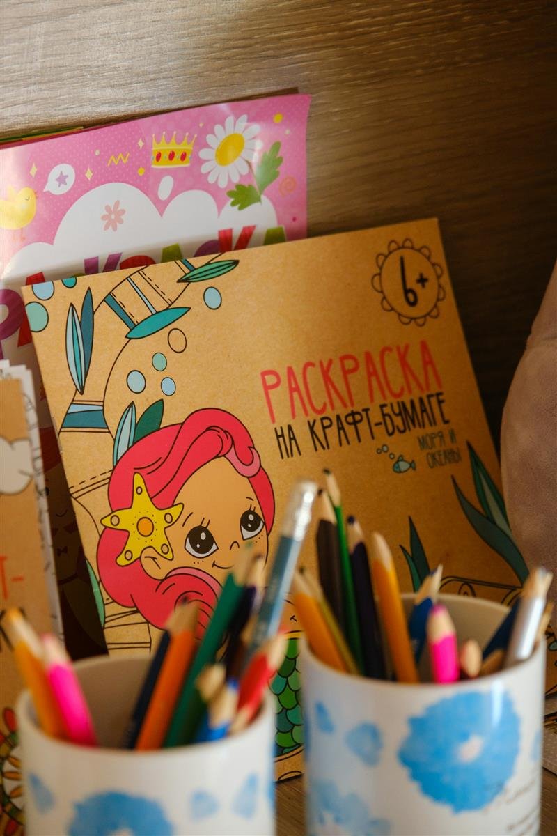 Livro de colorir aberto com lápis de cor coloridos ao lado
