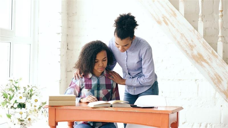 Mãe ajudando a filha com a lição de casa em uma escrivaninha