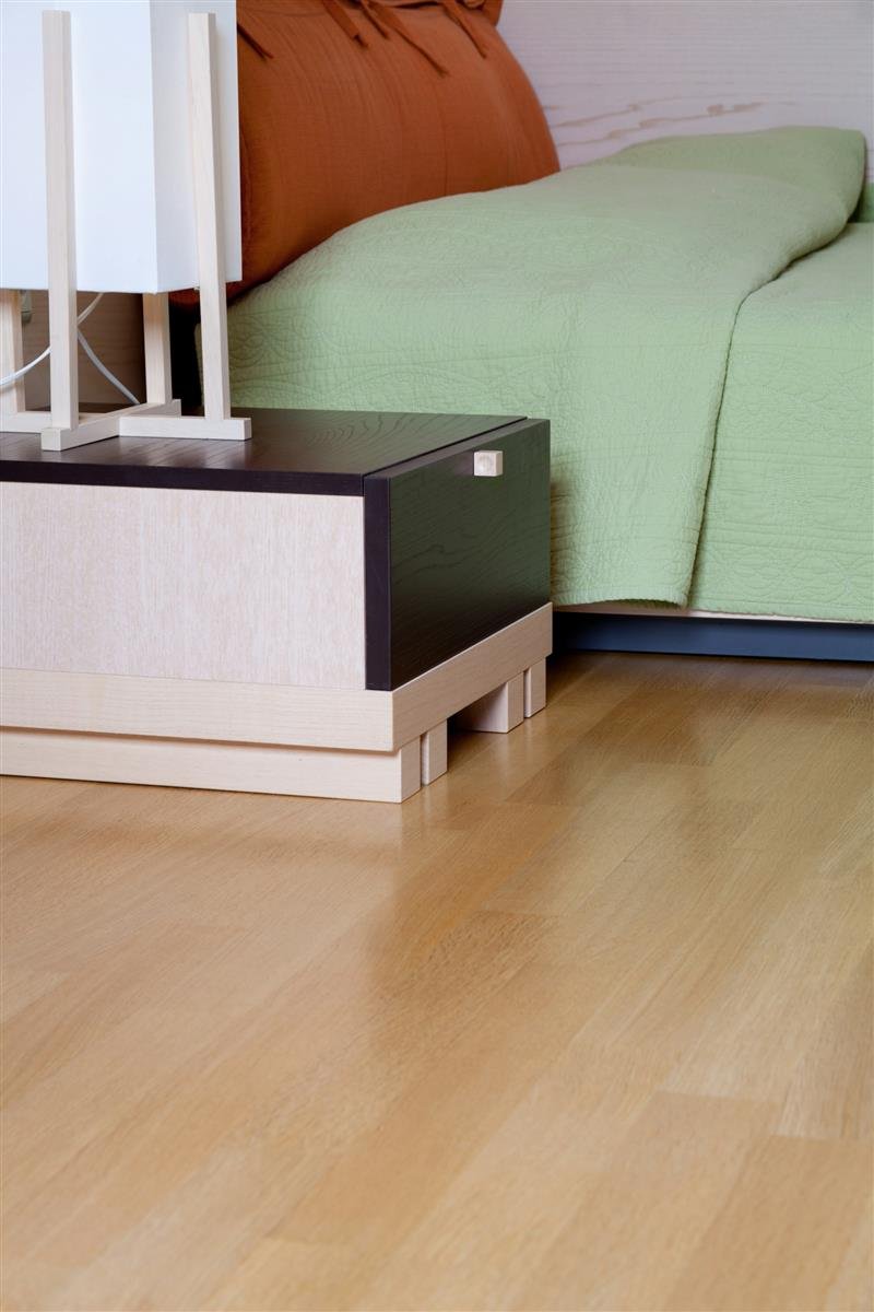Quarto com cama, criado-mudo e piso de madeira