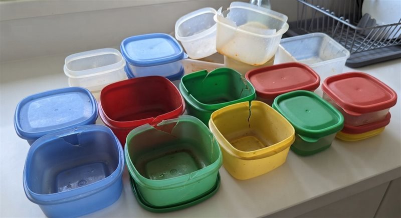 Potes de plástico coloridos sobre a bancada, alguns rachados, sendo separados no teste antes do descarte