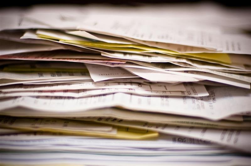 Pilha de papéis e documentos vista de perto sobre uma superfície clara